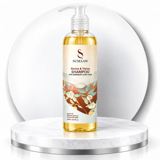 A bottle of Sumaaw Revive & Thrive Shampoo. The bottle is transparent and filled with golden-yellow liquid, featuring a beige label with botanical illustrations and a clear pump dispenser.